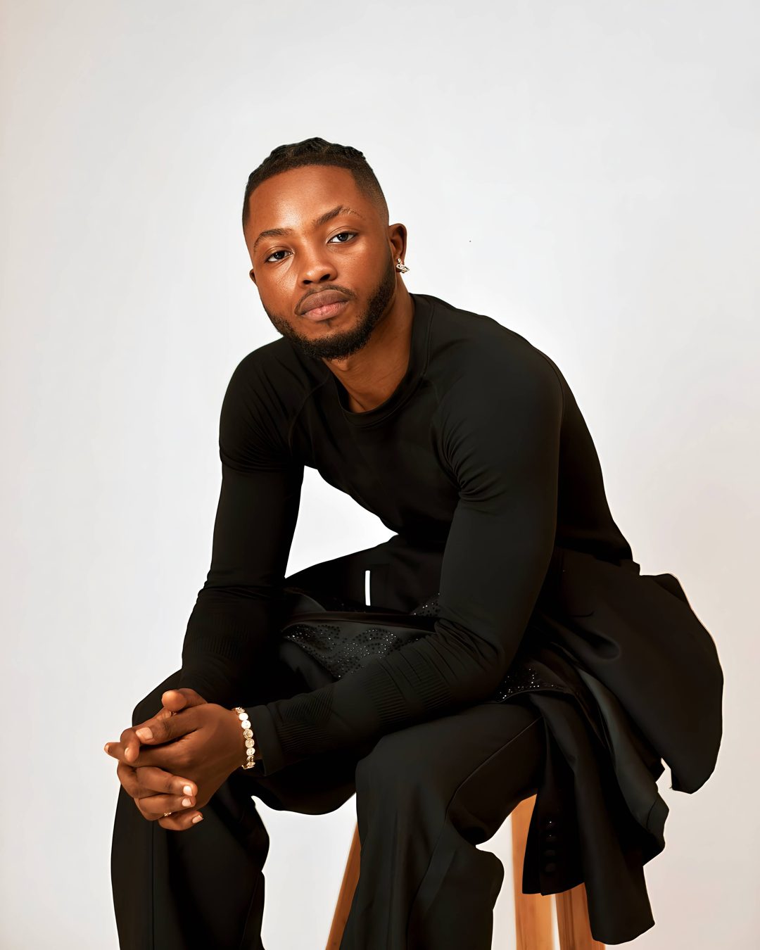 Rina Boy seated in a black studio outfit